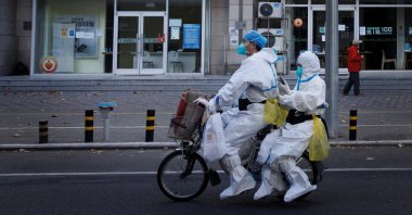 Pandemic prevention workers in protective suits ride an electric bike in Beijing, China, Nov. 21, 2022. (Reuters Photo)