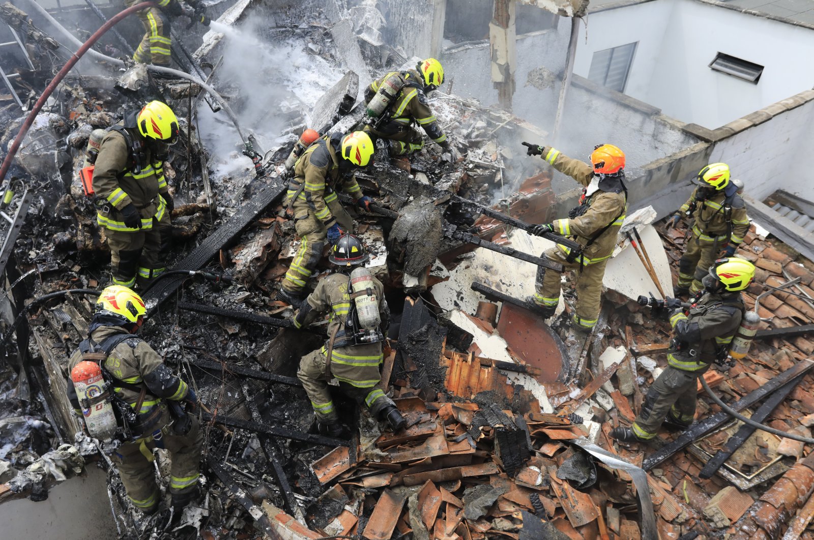 Firefighters work at the crash site of a small plane that fell on top of homes in a residential area of Medellin, Colombia, Monday, Nov. 21, 2022. (AP Photo)