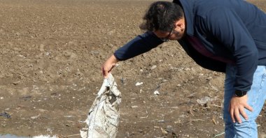 Sedat Gündoğdu holds a plastic bag left in a field, Çukurova, Türkiye, Nov. 22, 2022.  (DHA Photo)