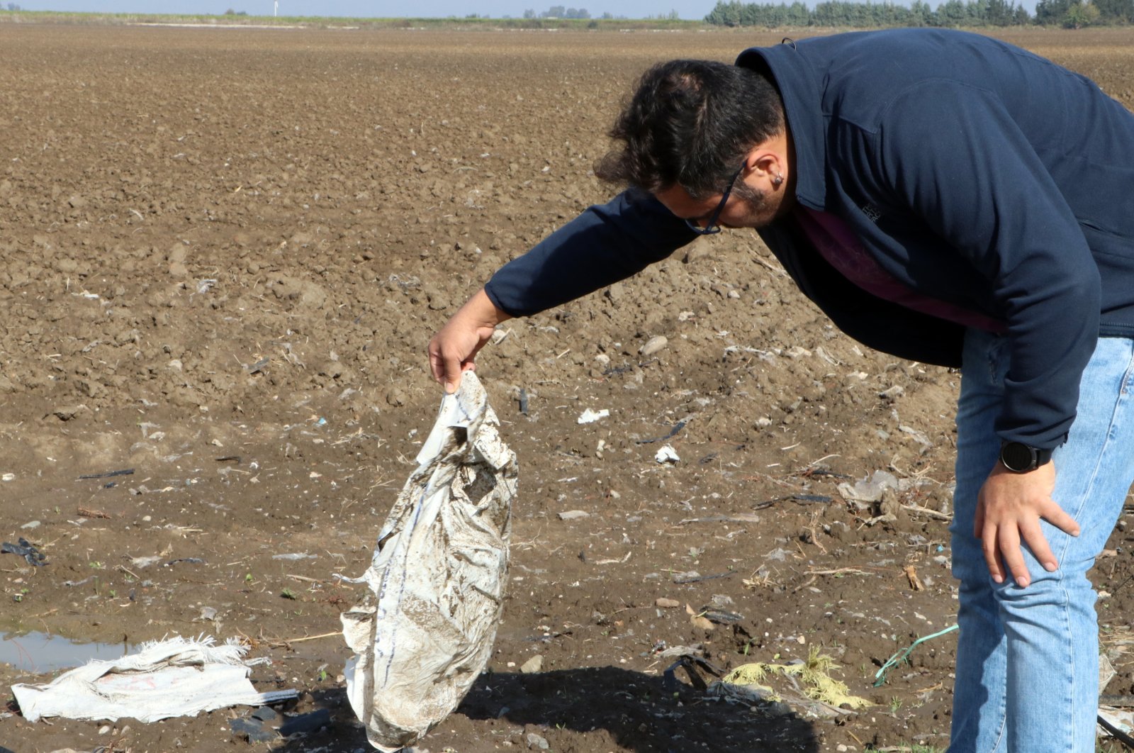 Sedat Gündoğdu holds a plastic bag left in a field, Çukurova, Türkiye, Nov. 22, 2022.  (DHA Photo)