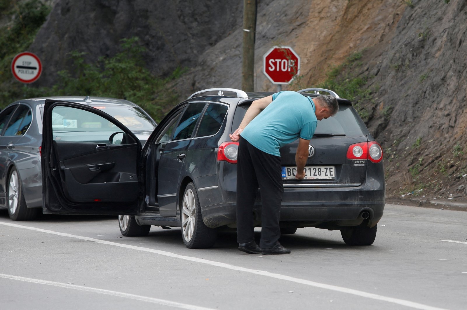 A driver removes a sticker covering the national markings on his car plates, Jarinje border crossing, Kosovo, Sept. 1, 2022. (Reuters Photo)