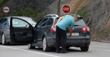 A driver removes a sticker covering the national markings on his car plates at the Jarinje border crossing, Kosovo, Sept. 1, 2022. (Reuters Photo)