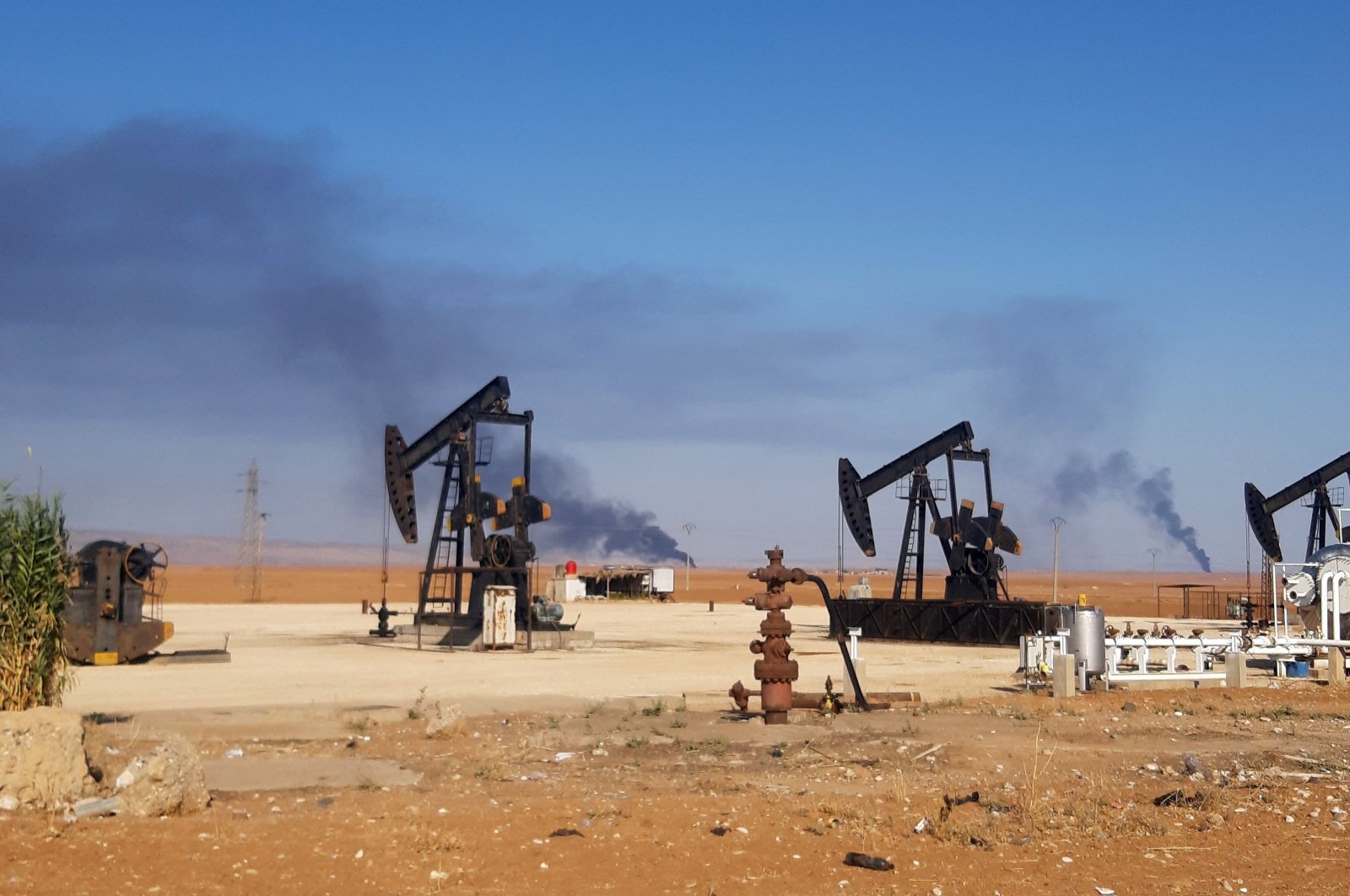 This picture shows pumpjacks in an oil field and smoke plumes rising in the background, following reported Turkish drone strikes near the town of al-Qahtaniyah in Syria&#039;s northeastern Hassakeh province, close to the border with Türkiye, Nov. 23, 2022.  (AFP Photo)