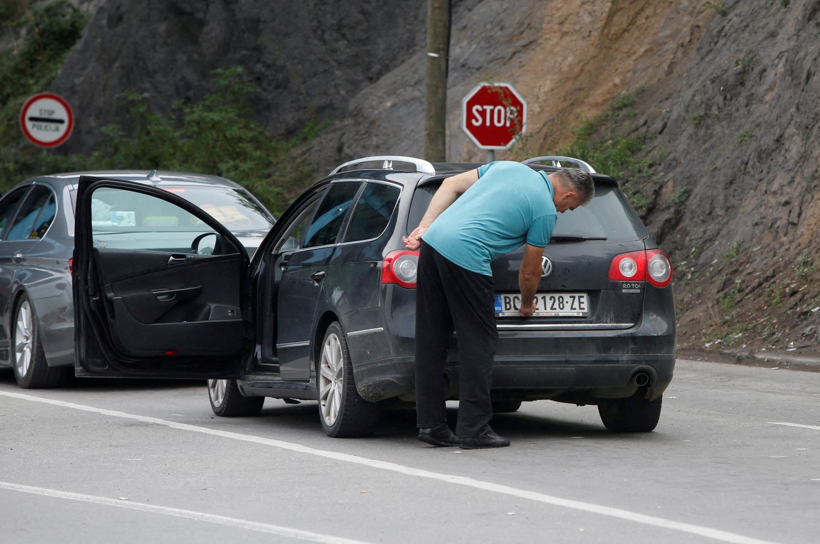 A driver removes a sticker covering the national markings on his car plates at the Jarinje border crossing, Kosovo, Sept. 1, 2022. (Reuters Photo)