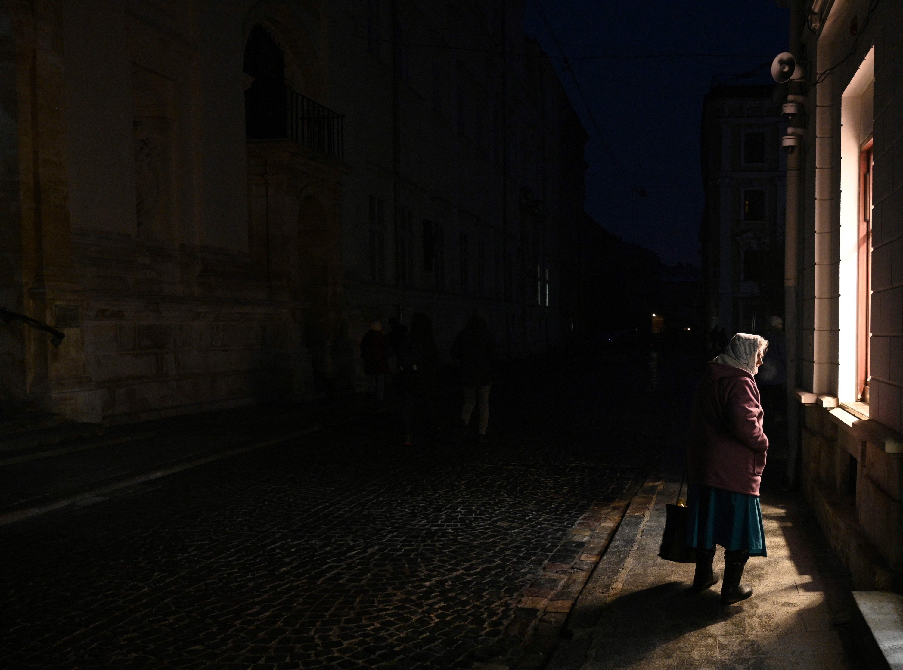 Seorang wanita berjalan di jalan saat pemadaman listrik setelah serangan Rusia di Lviv, Ukraina, 23 November 2022. (Foto AFP)
