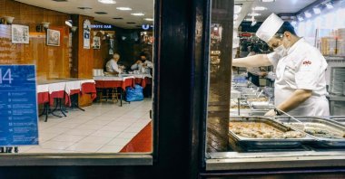 A worker stands behind a counter in a partially empty restaurant on Istiklal Street in Istanbul, Türkiye, Dec. 15, 2020. (AFP Photo)