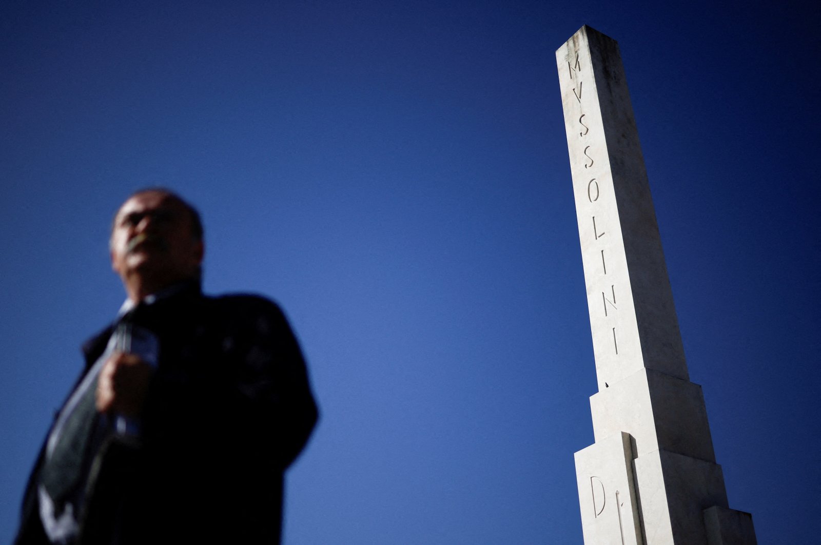 A man walks past an obelisk dedicated to fascist leader Benito Mussolini in Rome, Italy, Oct. 19, 2022. (Reuters Photo)