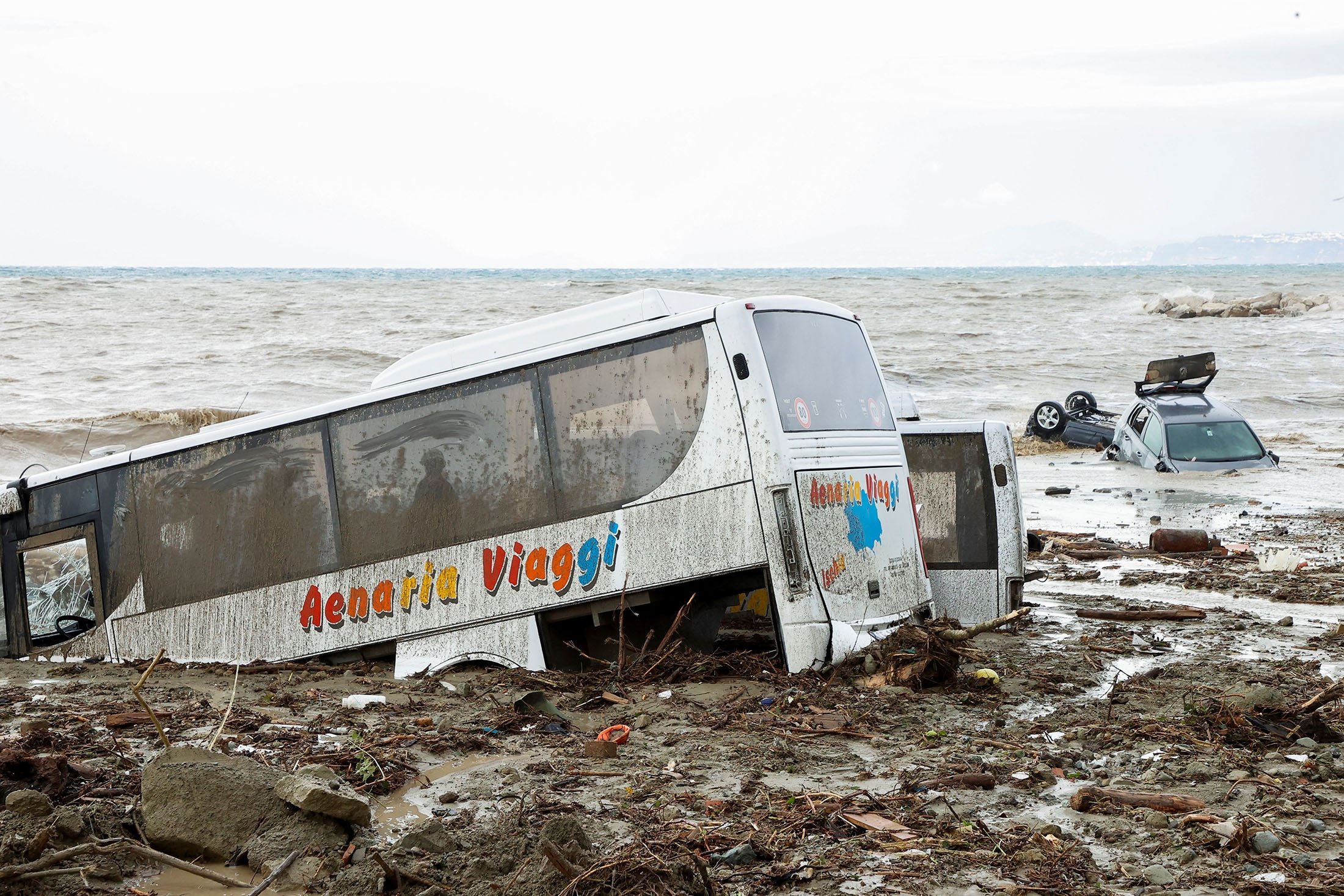 Mobil-mobil rusak terlihat di tepi laut, menyusul tanah longsor di pulau liburan Italia Ischia, Italia, 26 November 2022. (Foto Reuters)