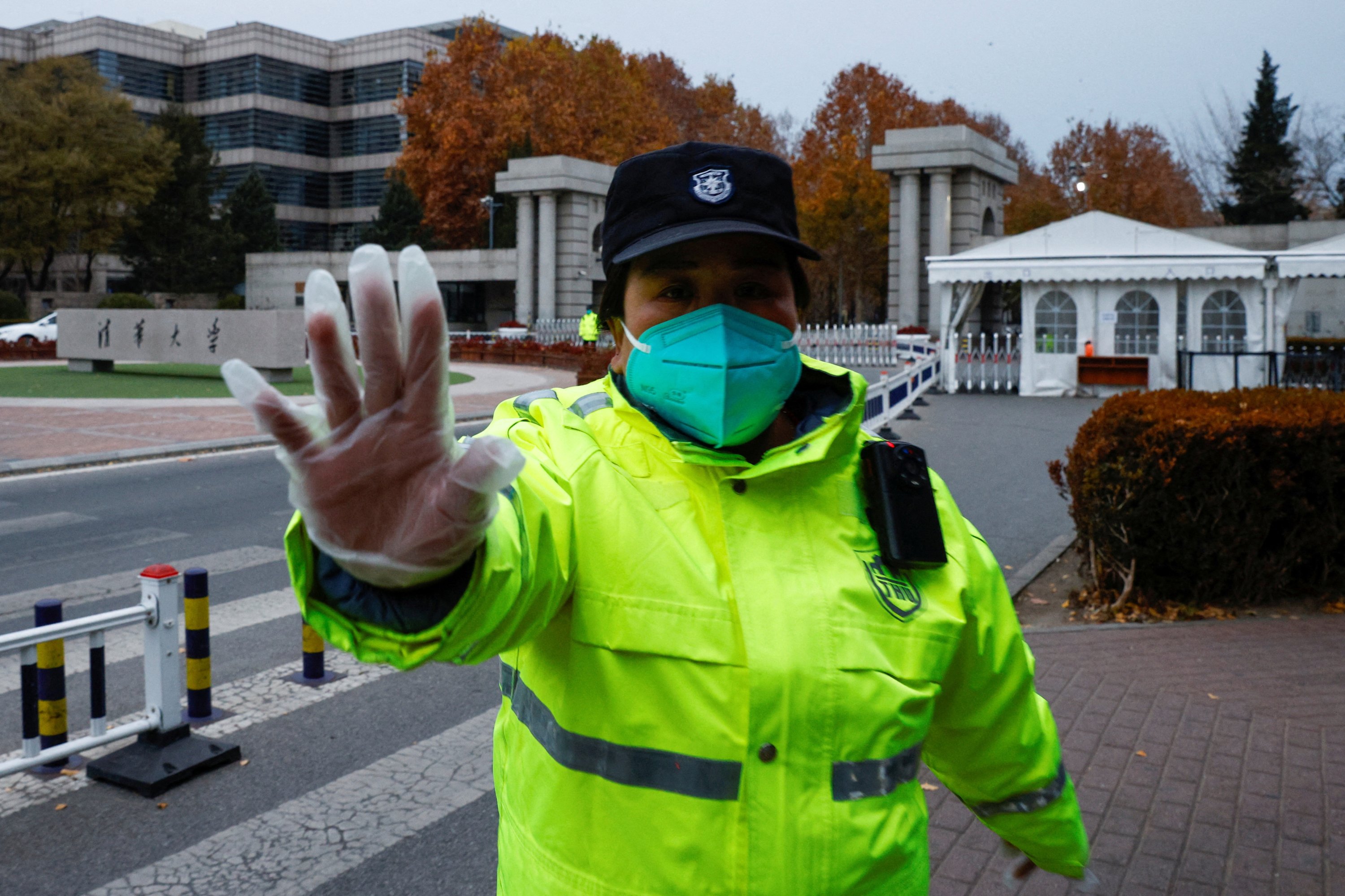 Seorang petugas keamanan berusaha mencegah pengambilan gambar, di gerbang Universitas Tsinghua, Beijing, China, 27 November 2022. (Foto Reuters)