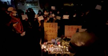 This picture obtained from a social media video shows people holding signs and lighting candles during a vigil held for the victims of the Urumqi fire, in Shanghai, China, Nov. 26, 2022. (Reuters Photo)