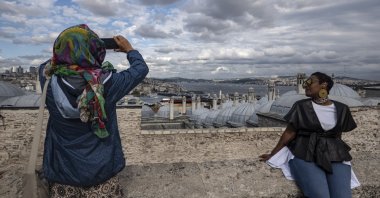 Tourists take pictures in the Süleymaniye Mosque backdropped by the Bosporus in Istanbul, Türkiye, Oct. 4, 2022. (EPA Photo)