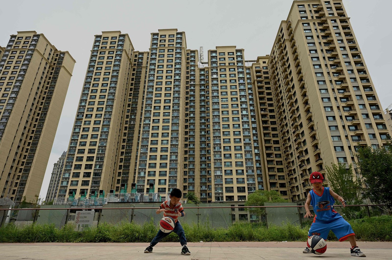 This file photo shows children playing basketball in front of a housing complex constructed by Chinese property developer Evergrande in Beijing, China, July 28, 2022. (AFP Photo)