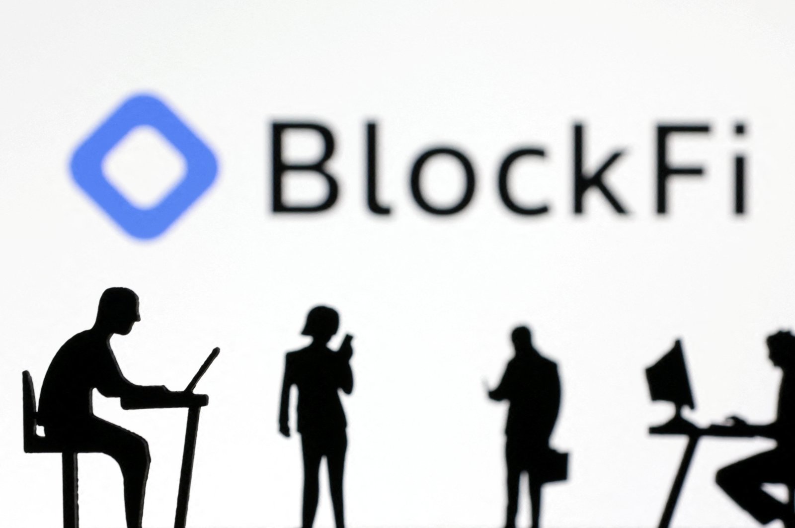 Figurines with smartphones and computers are seen in front of the BlockFi logo in this illustration, Nov. 28, 2022. (Reuters Photo)