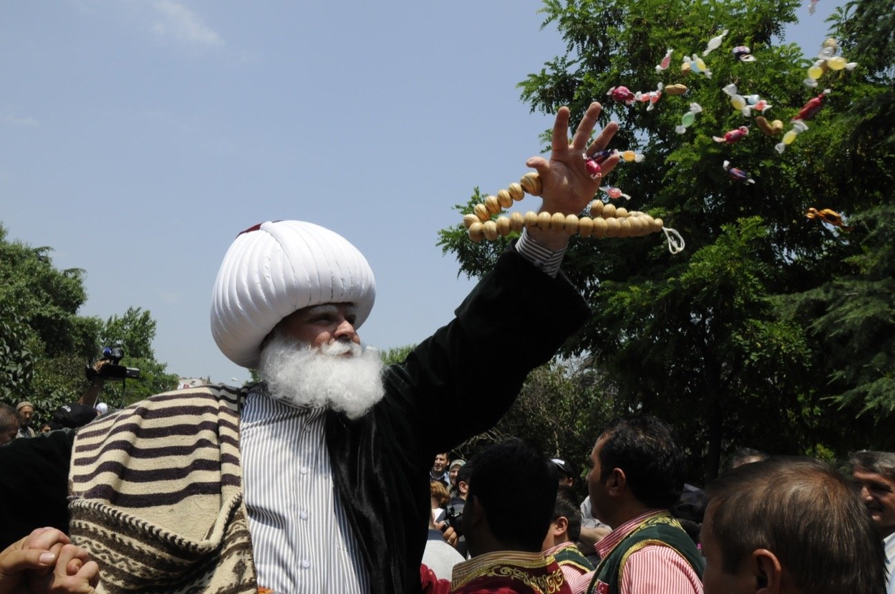 Seorang pria berpakaian tradisional membagikan permen di Festival Akşehir Nasreddin Hodja.  (Foto milik Kementerian Kebudayaan dan Pariwisata Türkiye)