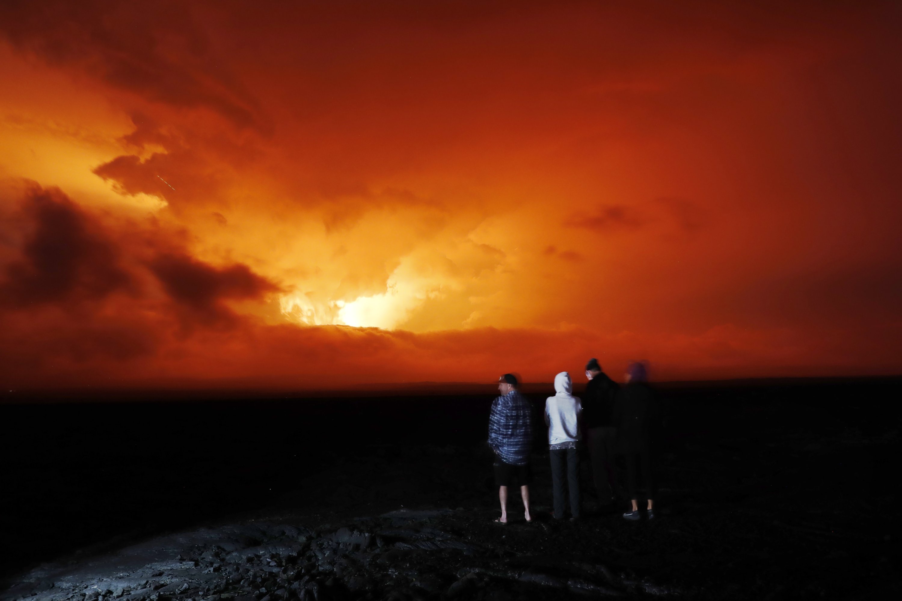 Orang-orang menyaksikan letusan Mauna Loa, dekat Hilo, Hawaii, AS, 28 November 2022. (Foto AP)