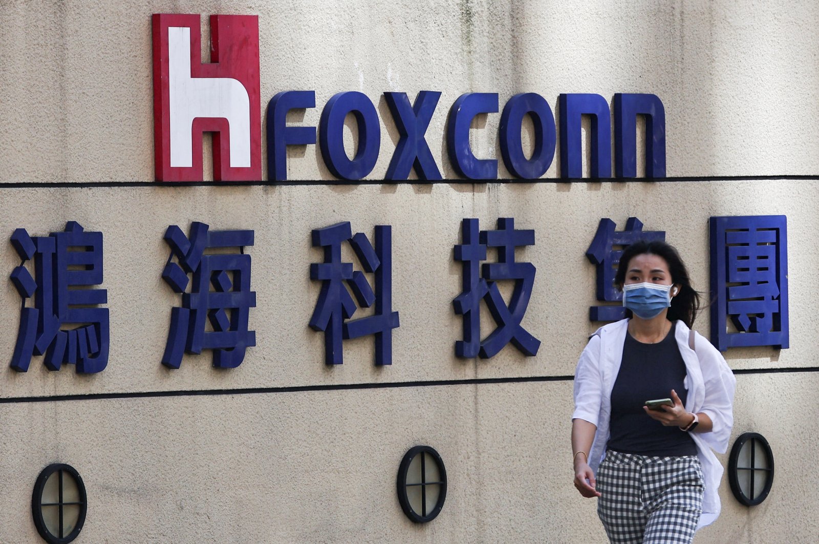 A woman walks past the logo of Foxconn outside the company&#039;s building in Taipei, Taiwan, Nov., 9, 2022. (Reuters Photo)