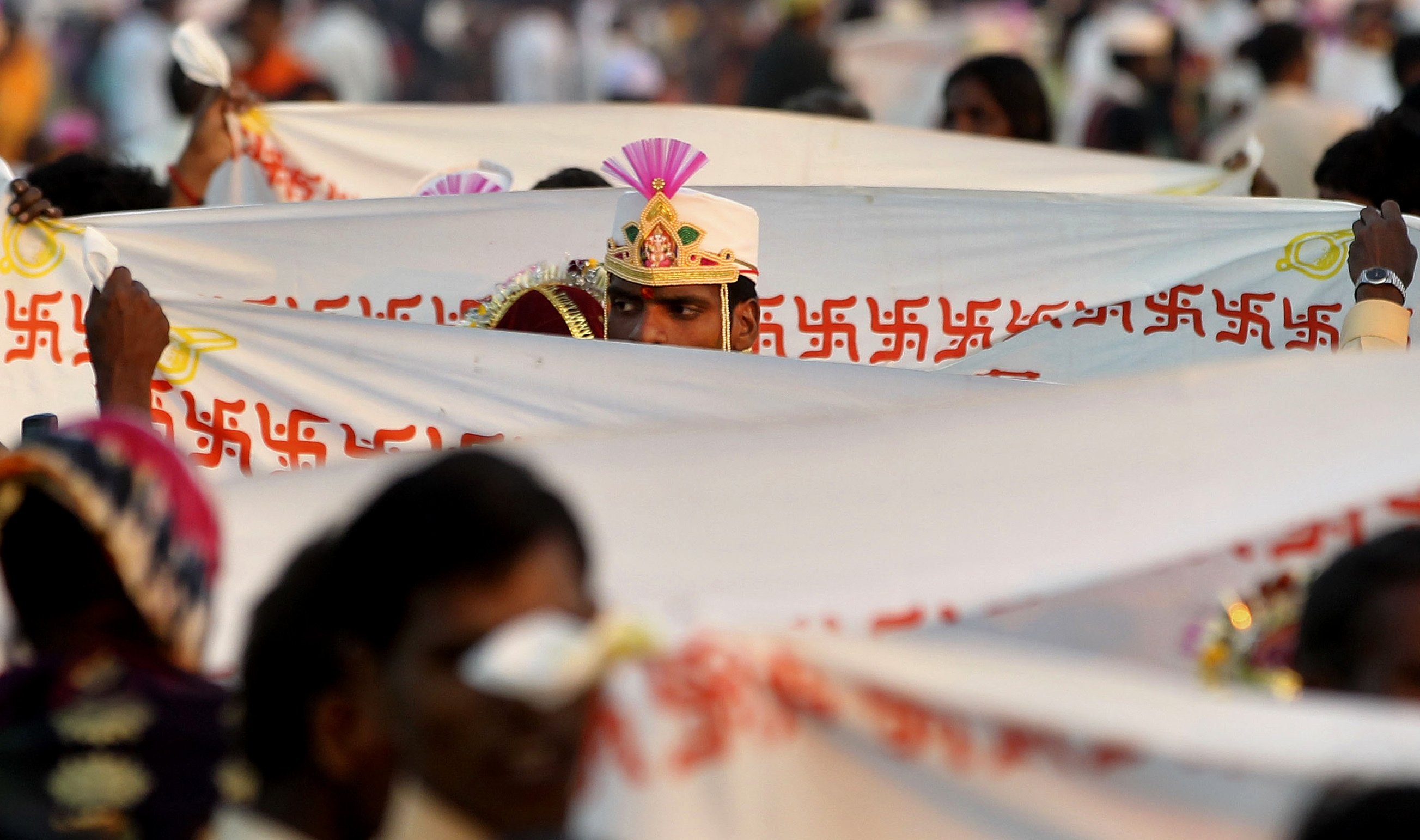 Seorang mempelai pria berdiri di belakang kain berlambang swastika Hindu selama ritual pada upacara pernikahan massal di Virar, di pinggiran Mumbai, India, 29 Januari 2012. (Foto AP)