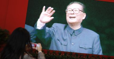 People take photos of a poster showing former Chinese President Jiang Zemin, Beijing, China, Nov. 30, 2022. (IHA Photo)