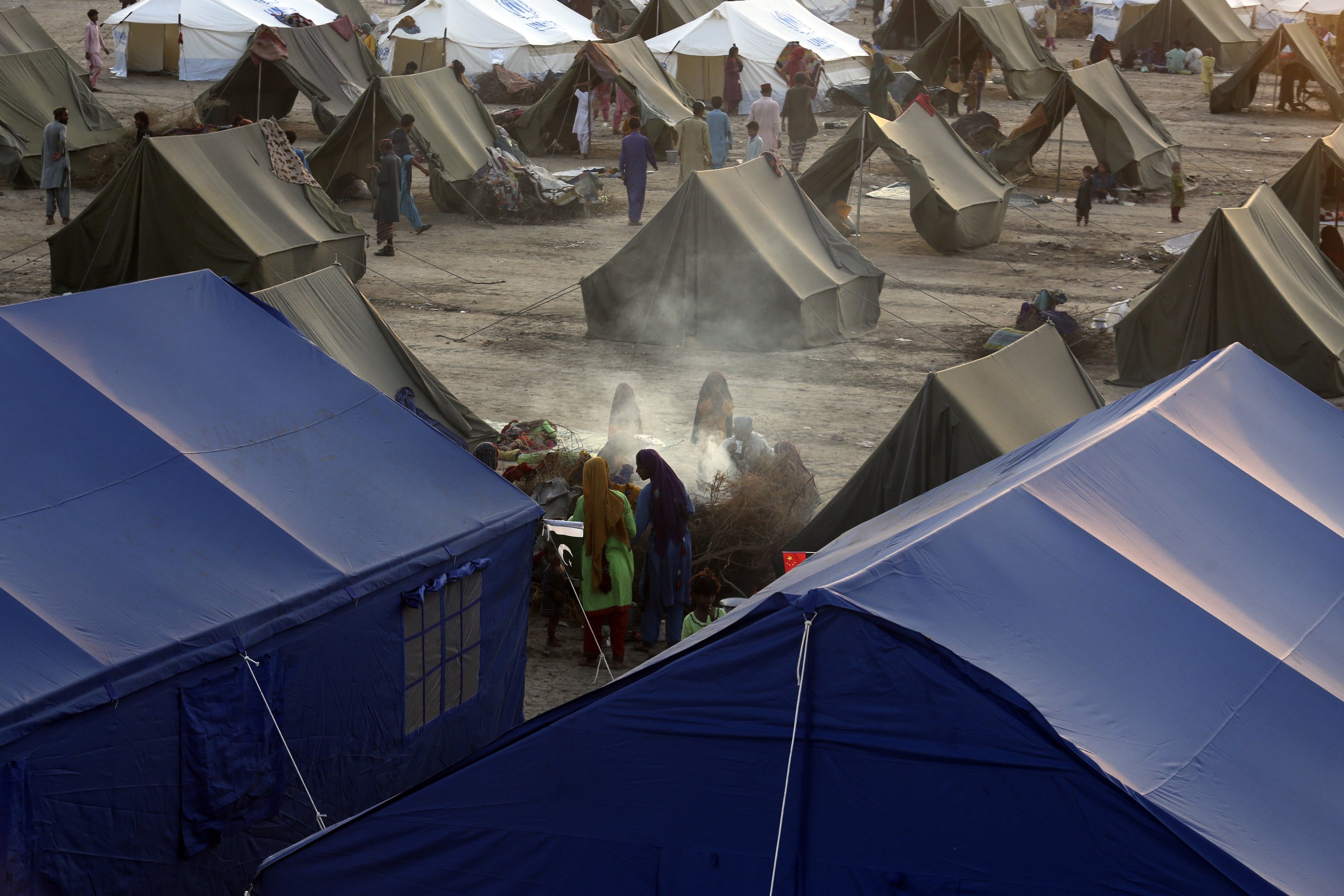 Para korban banjir besar akibat hujan muson berlindung saat mereka menyiapkan teh di kamp perumahan tenda sementara yang diselenggarakan oleh UNHCR, Sukkur, Pakistan, 10 September 2022. (Foto AP)