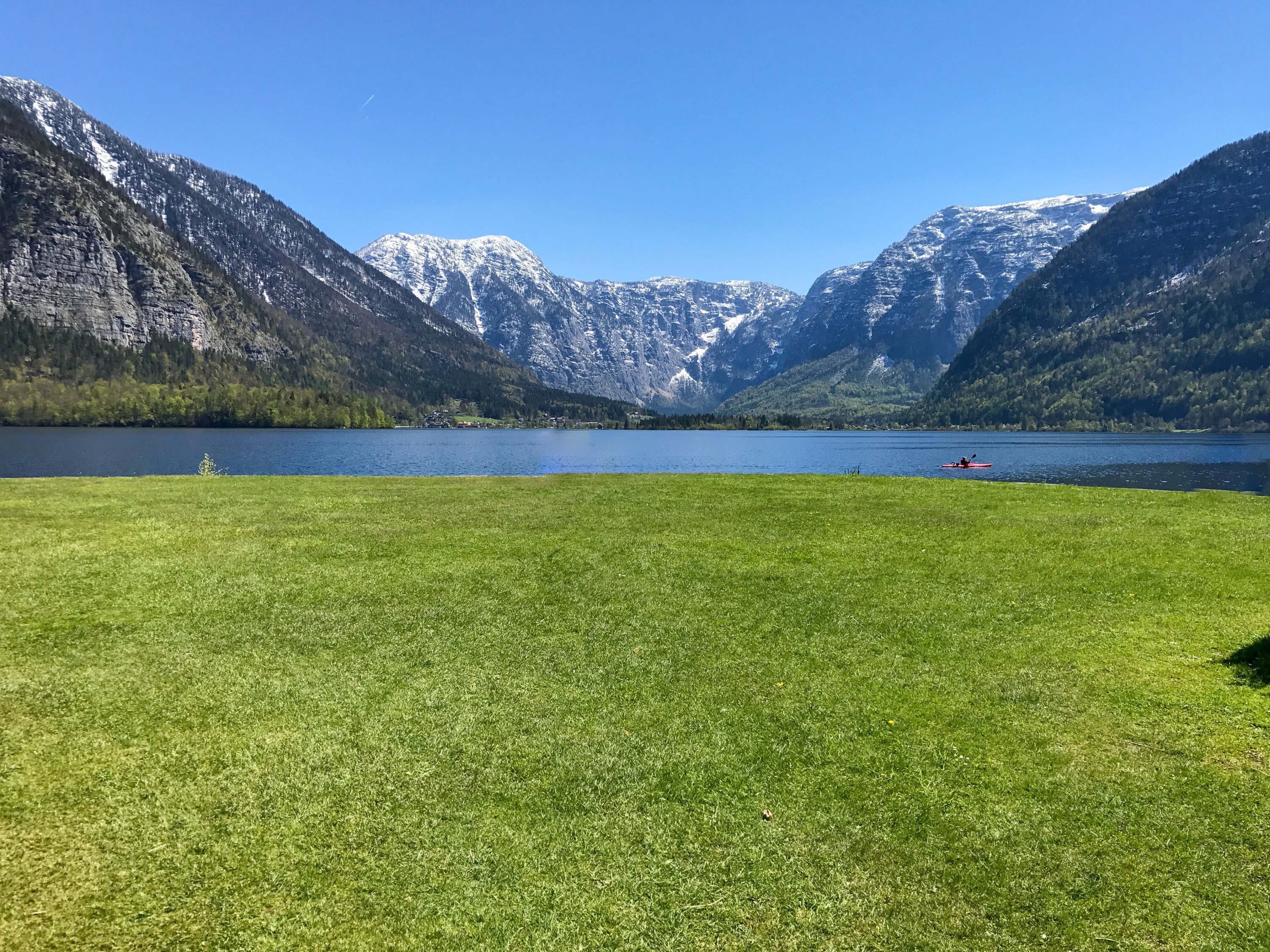 Pemandangan padang rumput hijau di depan danau dan Pegunungan Alpen, di Hallstatt, Austria.  (Foto oleh Özge Şengelen)