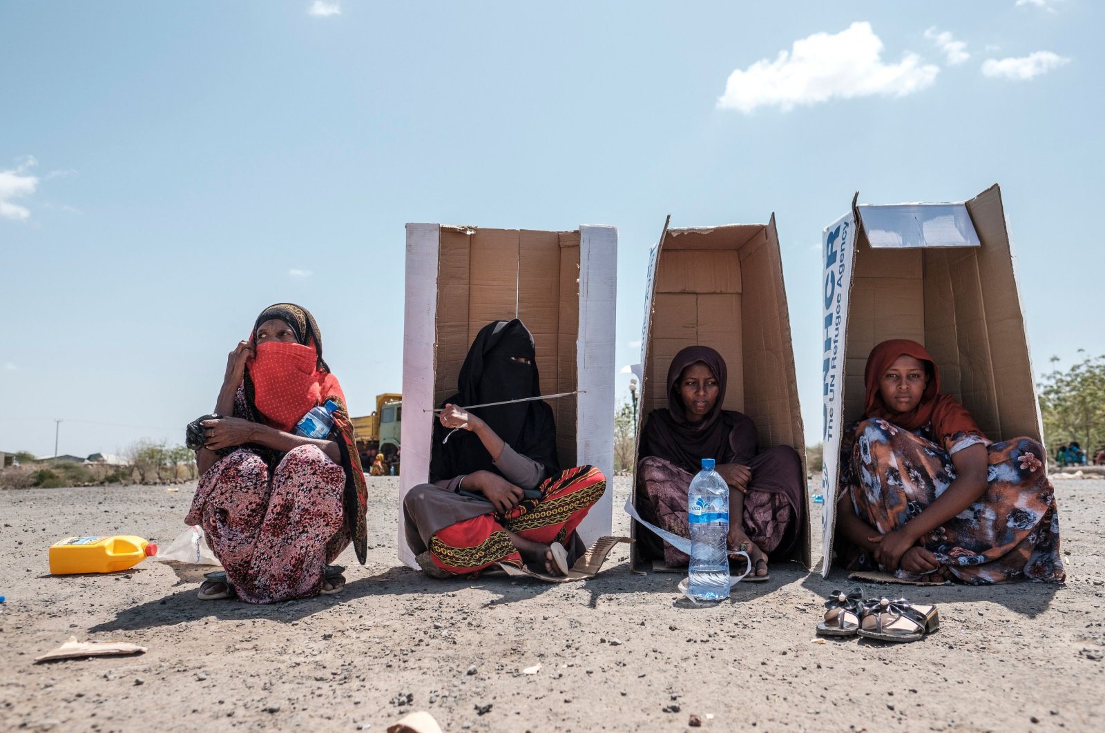 Women sit under UNHCR-branded cardboard boxes as they wait to be registered by the authorities, Semera, Ethiopia, Feb. 14, 2022. (AFP Photo)