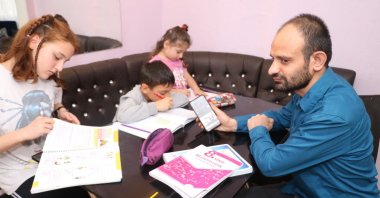 Cihan Dinçer, a visually impaired father, helps his kids with their homework in Zonguldak, Türkiye, Dec. 2, 2022. (IHA Photo)