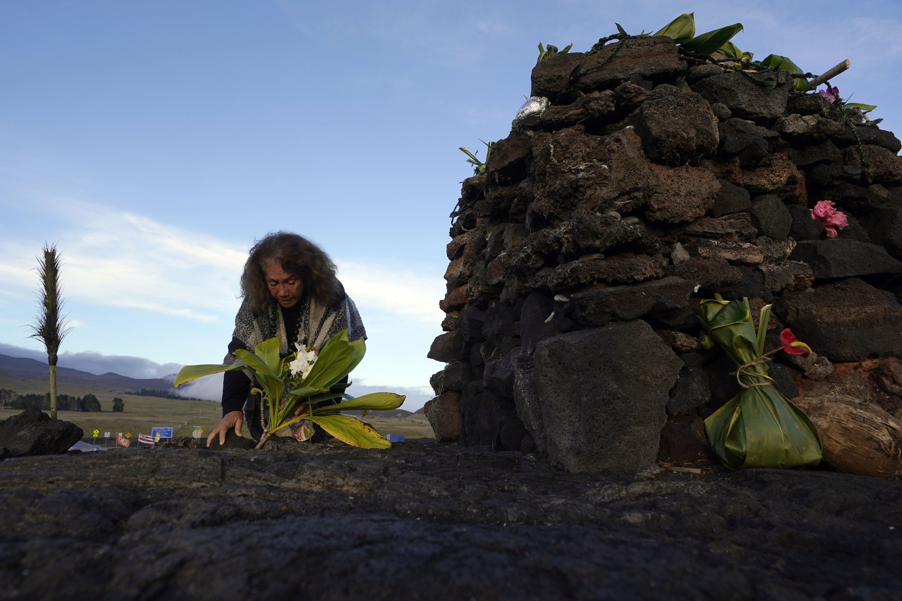 Illona Ilae, dari Kailua-Kona, Hawaii, meninggalkan persembahan di depan alter di bawah gunung berapi Mauna Loa saat meletus, dekat Hilo, Hawaii, AS, 1 Desember 2022. (Foto AP)