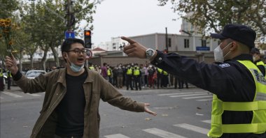 A protester holding flowers is confronted by a policeman during a protest on a street in Shanghai, China, Nov. 27, 2022. (AP Photo)