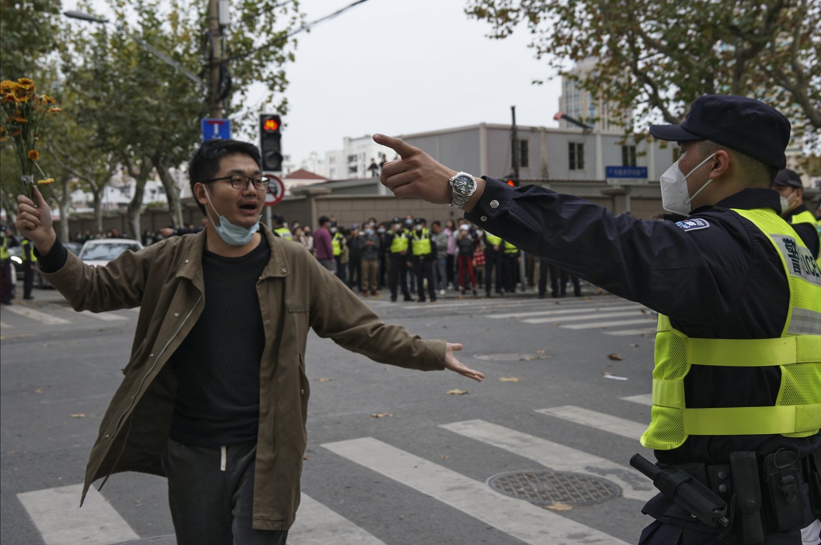 A protester holding flowers is confronted by a policeman during a protest on a street in Shanghai, China, Nov. 27, 2022. (AP Photo)