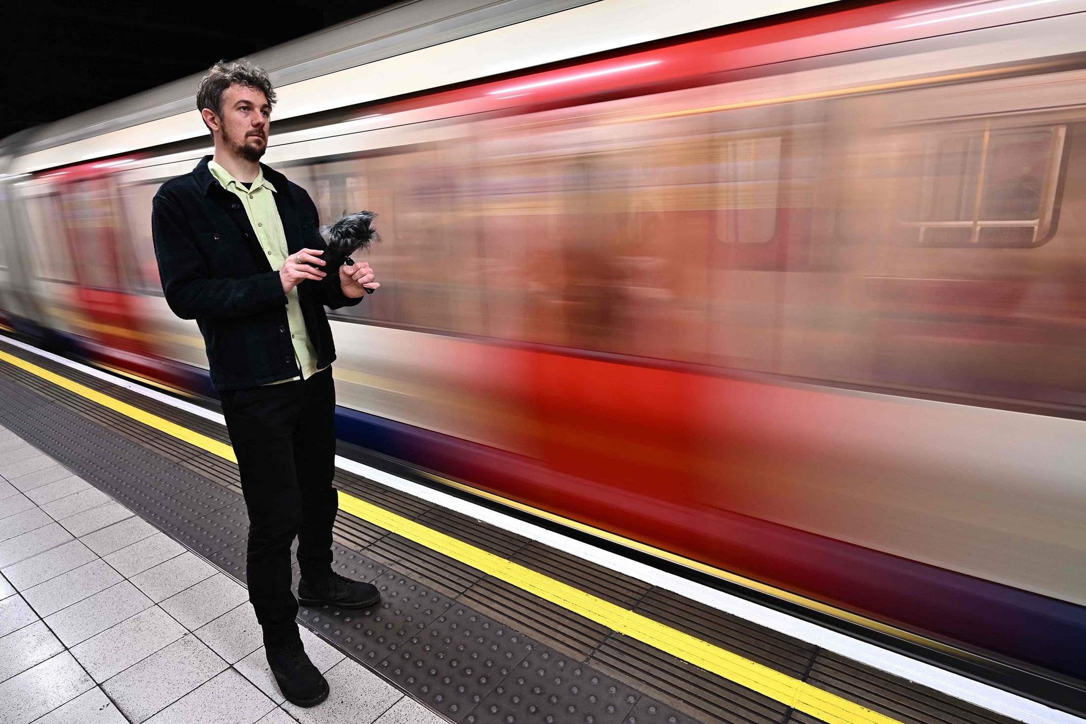 Musisi dan artis suara Stuart Fowkes merekam suara kereta bawah tanah London yang lewat di stasiun tabung Blackfriars di London, Inggris, 28 November 2022. (Foto AFP)