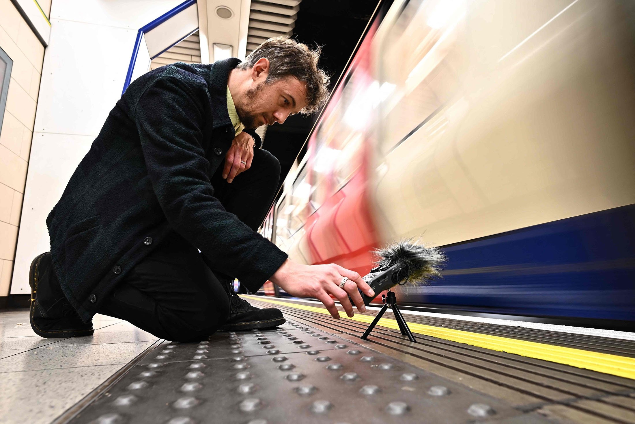 Musisi dan artis suara Stuart Fowkes merekam suara kereta bawah tanah London yang lewat di stasiun tabung Blackfriars di London, Inggris, 28 November 2022. (Foto AFP)