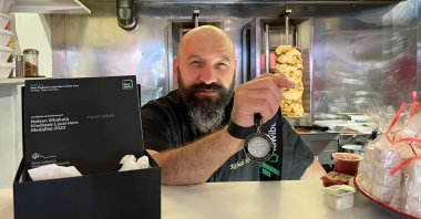 Yusuf Corten shows his medal in his restaurant, in Nelson, New Zealand, Dec. 3, 2022. (AA Photo) 