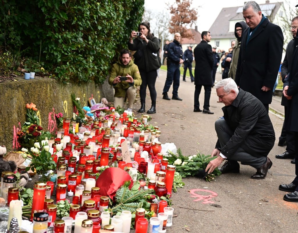 Thomas Strobl (kneeling), interior minister of Baden-Württemberg, and Ahmet Başar Şen (R), Türkiye&#039;s ambassador to Germany, lay a wreath at the scene of a knife attack on two girls during a moment of silence. (Getty Images)
