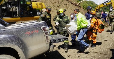 Rescuers carry the body of a deceased person after a bus was buried by a landslide, Pueblo Rico, Colombia, Dec. 5, 2022. (Reuters Photo)