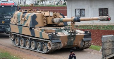 In this file photo taken on February 12, 2020, a child walks past a Turkish self-propelled artillery gun in the town of Binnish in Syria's northwestern province of Idlib, near the Syria-Türkiye border. (AFP Photo)