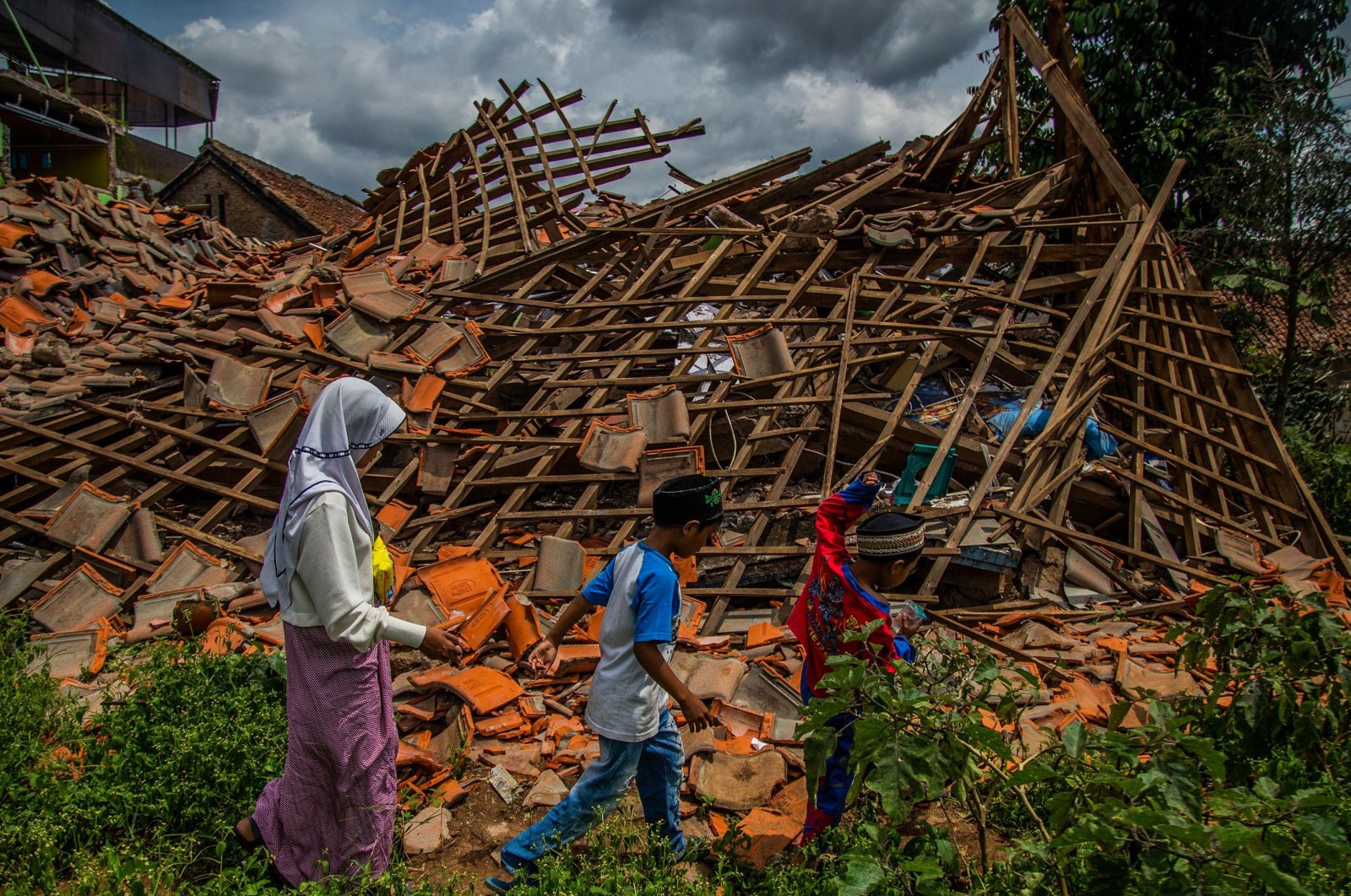 Children walk past a house that collapsed in an earthquake, Cianjur, West Java, Indonesia, Dec. 1, 2022. (AFP Photo)