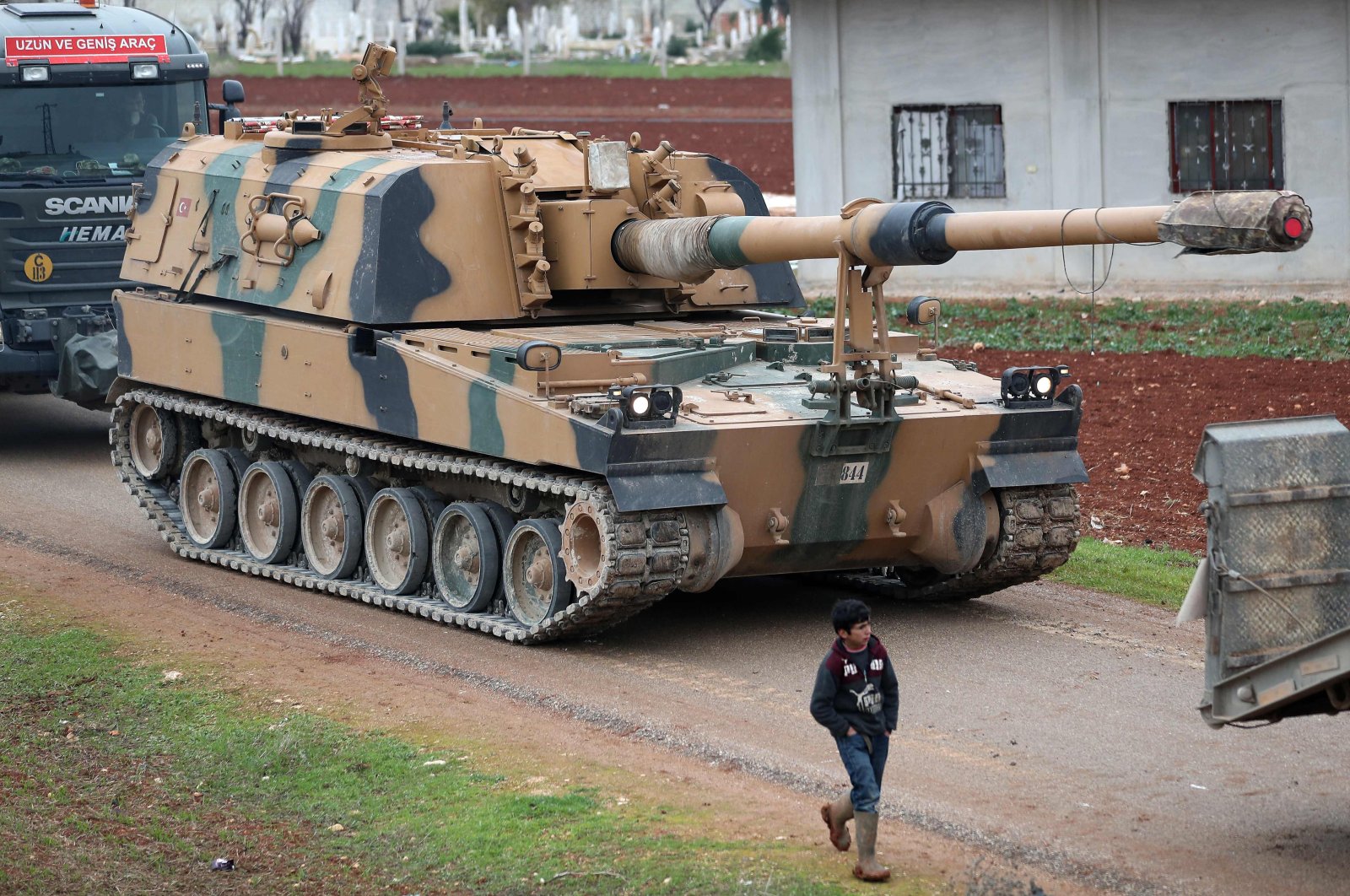 In this file photo taken on February 12, 2020, a child walks past a Turkish self-propelled artillery gun in the town of Binnish in Syria&#039;s northwestern province of Idlib, near the Syria-Türkiye border. (AFP Photo)
