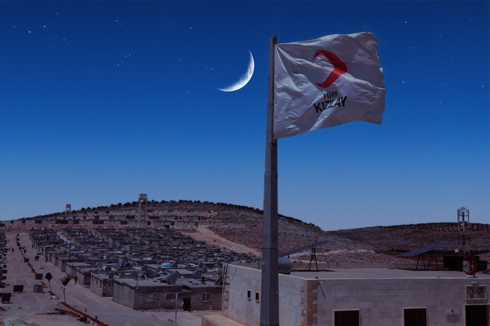 A Turkish Red Crescent (Kızılay) flag flies over a cluster of briquette homes Türkiye has constructed in northern Syria. Dec. 7, 2022. (Photo by Uğur Yıldırım)