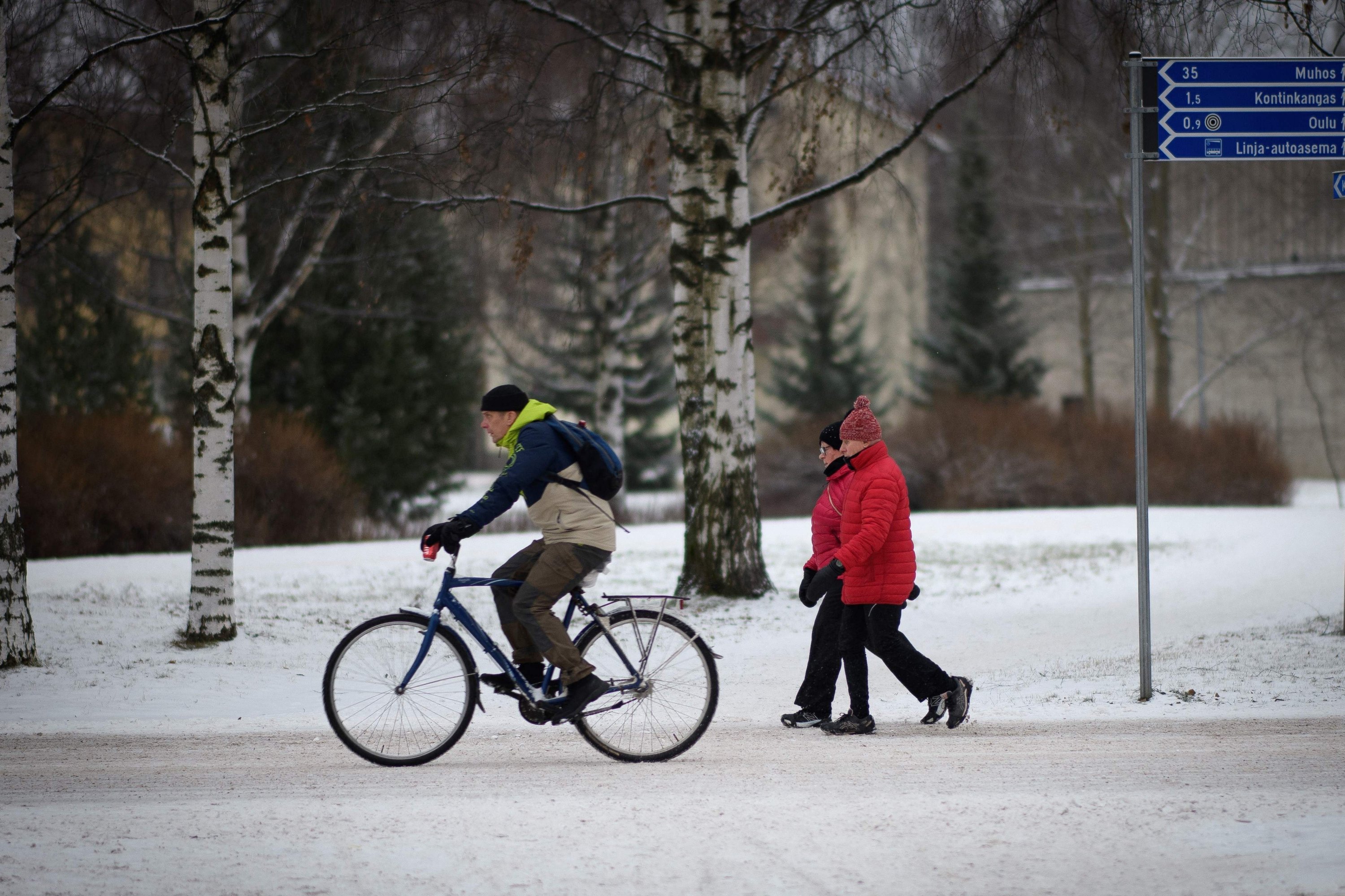 Seorang pria mengendarai sepeda di jalur sepeda bersalju, di Oulu, Finlandia, 1 Desember 2022. (Foto AFP)