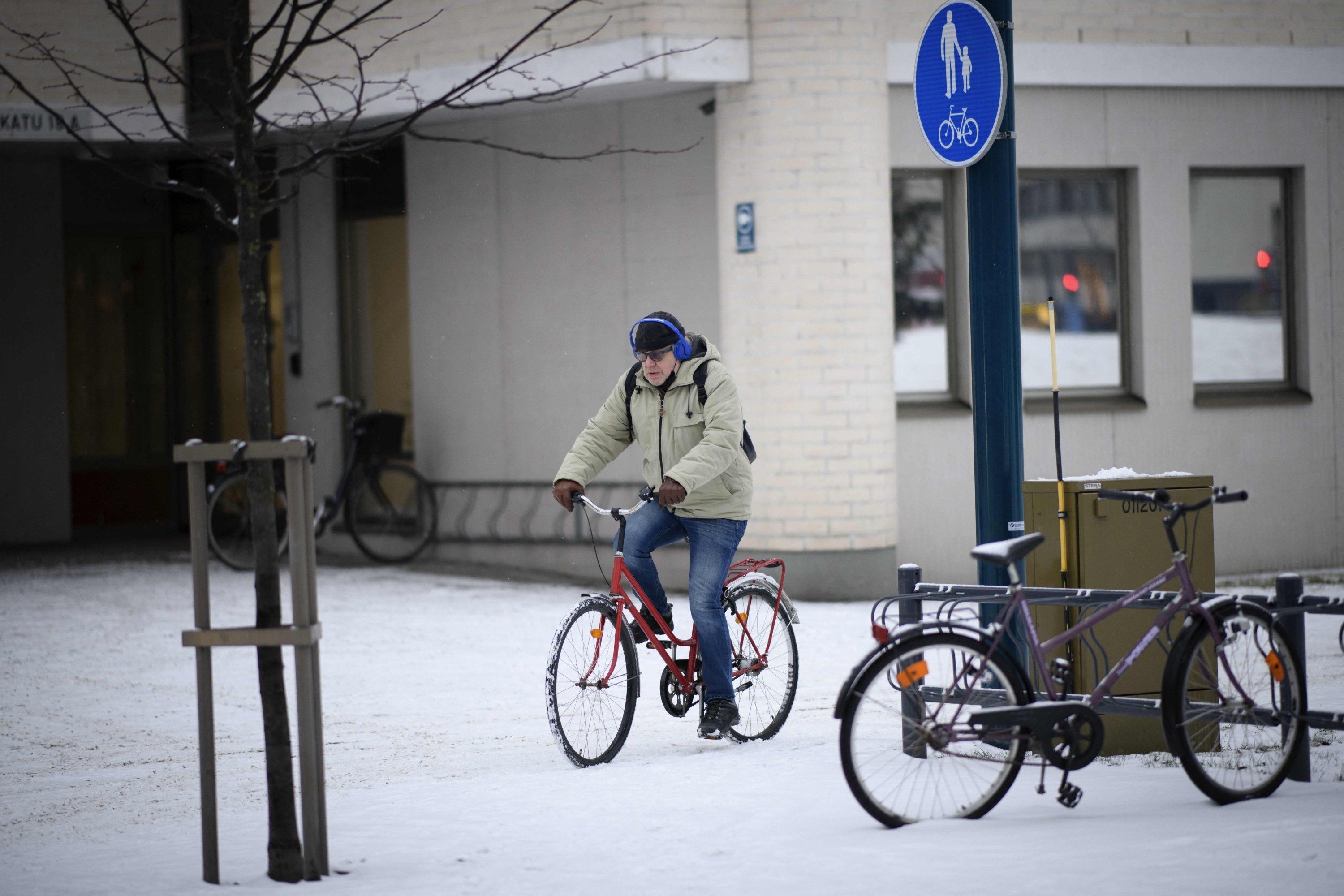 Seorang pria mengendarai sepeda di jalur sepeda bersalju, di Oulu, Finlandia, 1 Desember 2022. (AFP Photo)