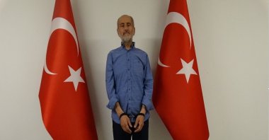 Greek National Intelligence Organization (EYP) spy Mohammed Amar Ampara, seen with handcuffs in front of two Turkish flags, after being caught by the National Intelligence Organization (MIT), Ankara, Türkiye, June 25, 2022. (DHA Photo)