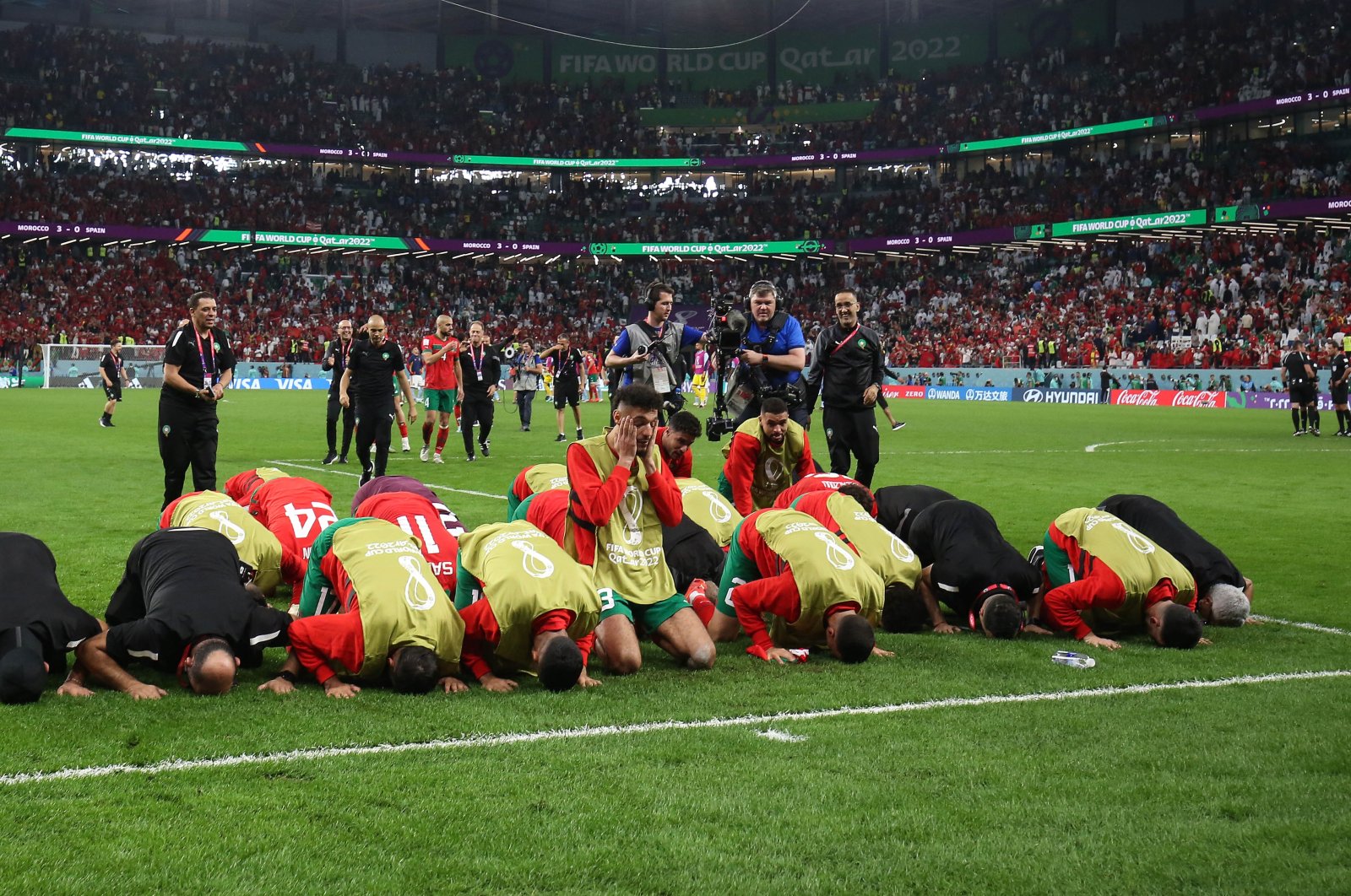 Morocco players and backroom staff kneel on the ground in prayer after their victory over Spain, Al Rayyan, Qatar, Dec. 6, 2022. (Getty Images Photo)