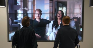 Office workers in London, watch the Duke and Duchess of Sussex's controversial documentary being aired on Netflix, in London, U.K., Dec. 8, 2022. (AP Photo)