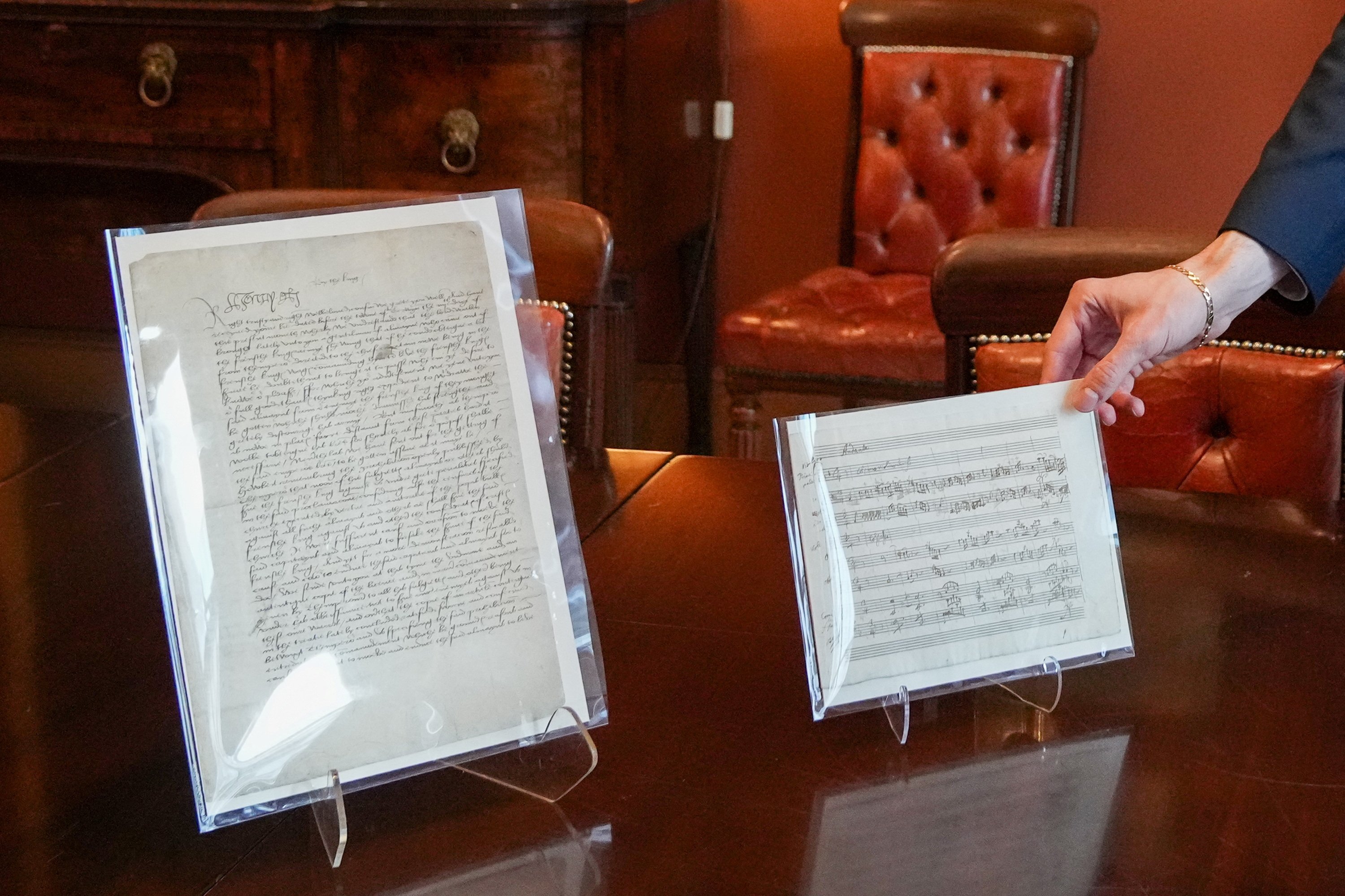 A person holds a rare signed letter from King Henry VIII to his lieutenant-general in France before the English victory at the Battle of the Spurs and autographed music manuscript by Wolfgang Amadeus Mozart, at Christie's in London, U.K., Dec. 7, 2022. (Reuters Photo)