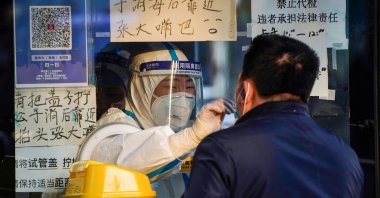 A medical worker in a protective suit collects a swab sample from a man at a nucleic acid testing site, as COVID-19 outbreaks continue, Shanghai, China, Dec. 12, 2022. (Reuters Photo)