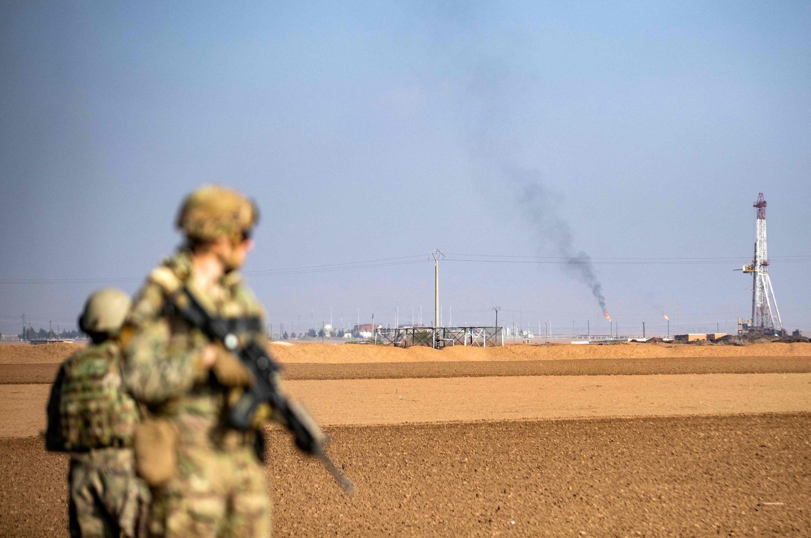 U.S. soldiers look toward a flare stack at a local oil field as they patrol the countryside of Rumaylan (Rmeilan) in Syria&#039;s northeastern Hasakeh province near the border with Türkiye, Dec. 4, 2022. (AFP Photo)