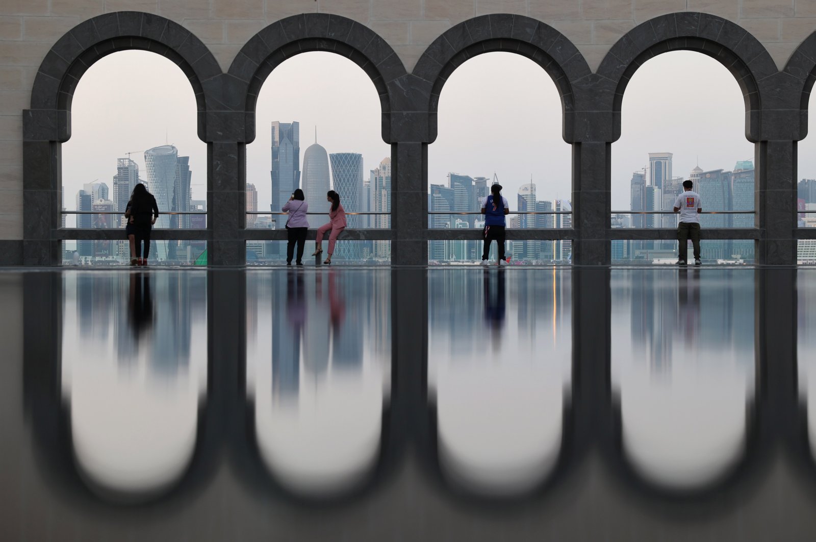 Visitors explore the Museum of Islamic Art (MIA), backdropped by the skyline of Doha, Qatar, Dec. 4, 2022. (EPA Photo)