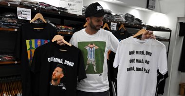 A man holds T-shirts with an image of Argentine forward Lionel Messi and a phrase reading "What are you looking at, you fool?" at a store in Buenos Aires, Argentina, Dec.12, 2022. (AFP Photo)