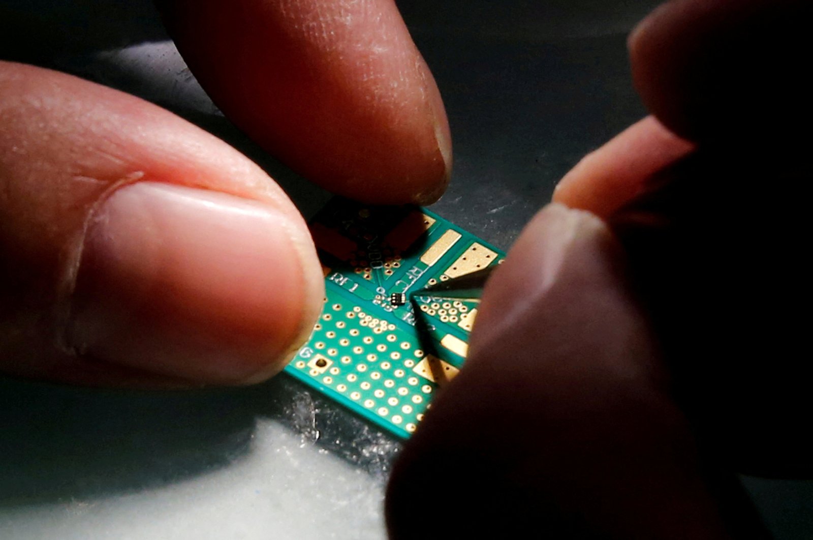 A researcher plants a semiconductor on an interface board during research work to design and develop a semiconductor product at Tsinghua Unigroup research center, Beijing, China, Feb. 29, 2016. (Reuters Photo)