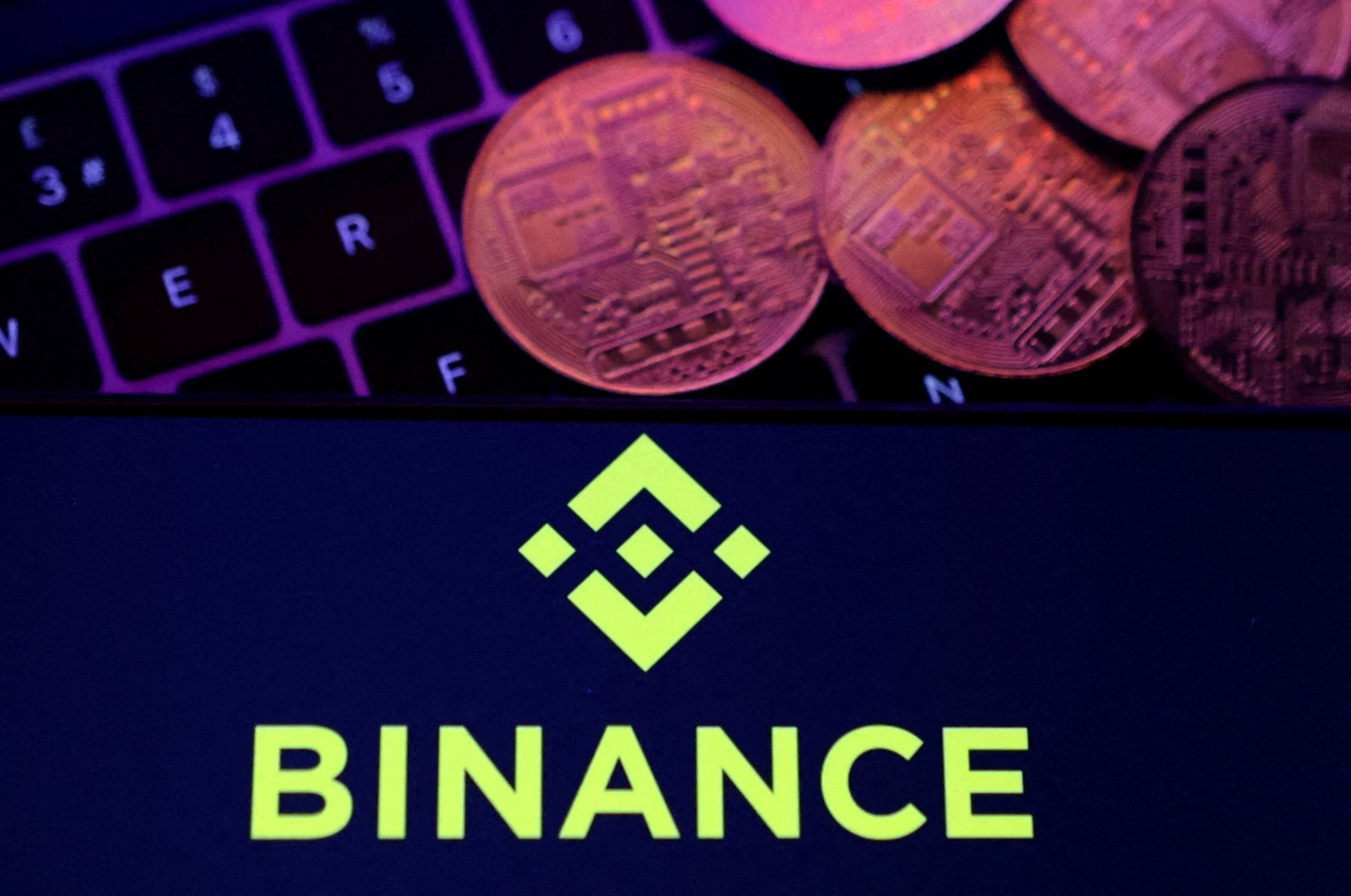 A smartphone displaying the Binance logo and a representation of cryptocurrencies on a keyboard are seen in this illustration, Nov. 8, 2022. (Reuters Photo)